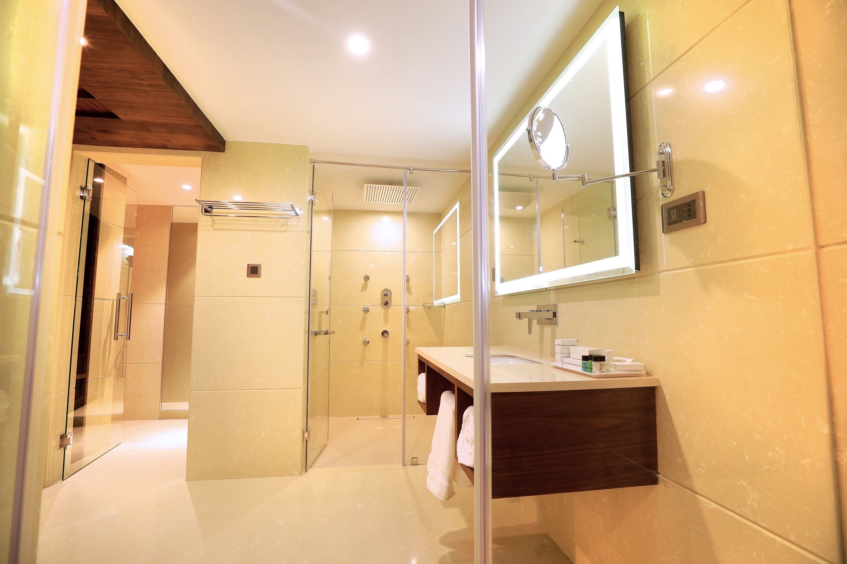 A modern bathroom with a glass-enclosed shower, a wooden vanity, and a large mirror.