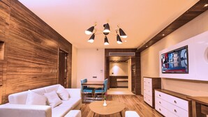 Una sala moderna con sofá, una mesa de centro y televisor montado en la pared.