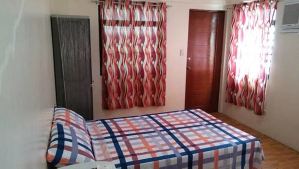 Un dormitorio con cama, una puerta y cortinas.