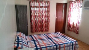 A bedroom with a bed, a door, and curtains.