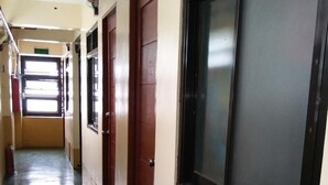 Un pasillo largo y estrecho con puertas a un lado y ventanas al otro.