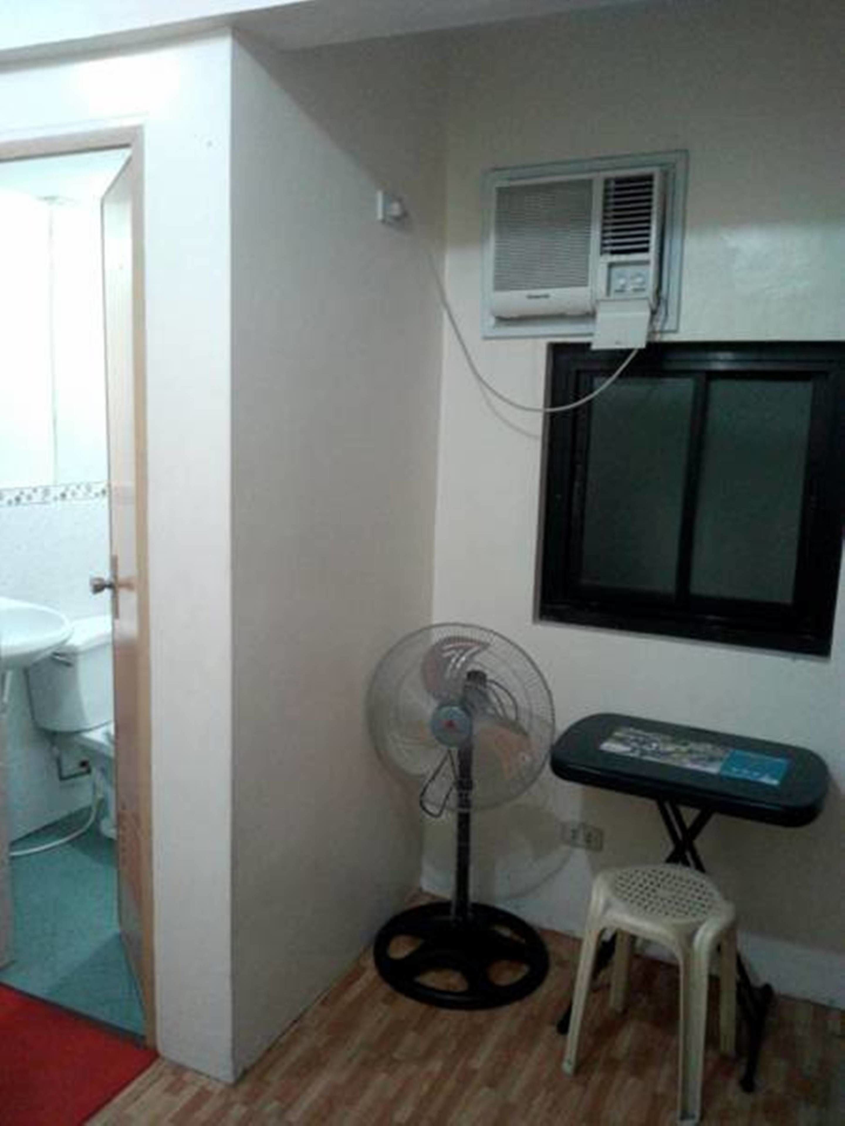 Une petite pièce avec un ventilateur, une fenêtre et un radiateur.