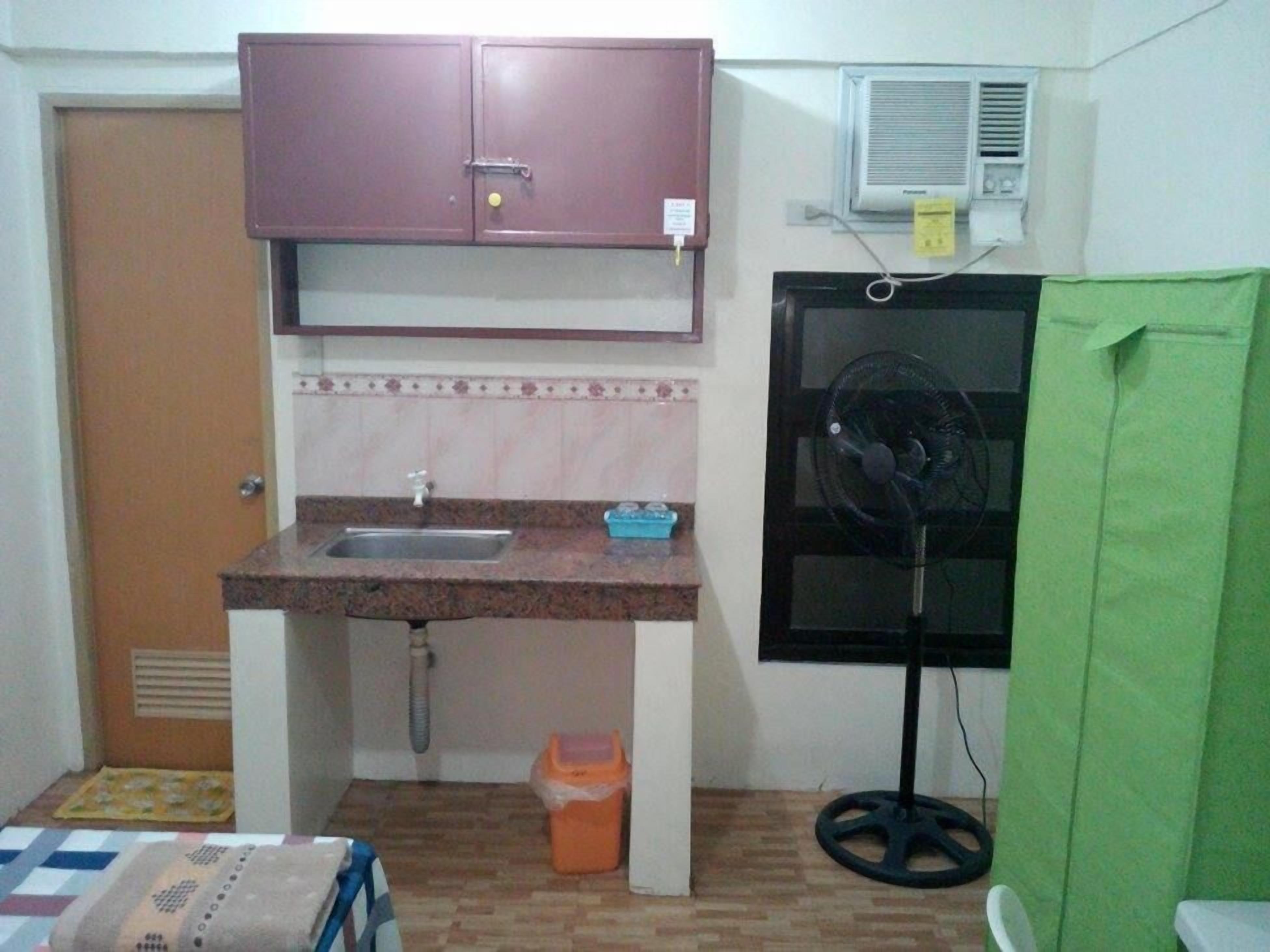 A small kitchenette with a sink, a cabinet, an air conditioner, and a fan.