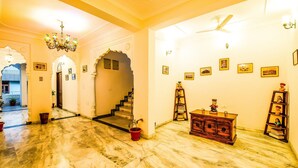 Um quarto amplo com piso de mármore, um lustre, um ventilador de teto e uma escada que leva a outro espaço.