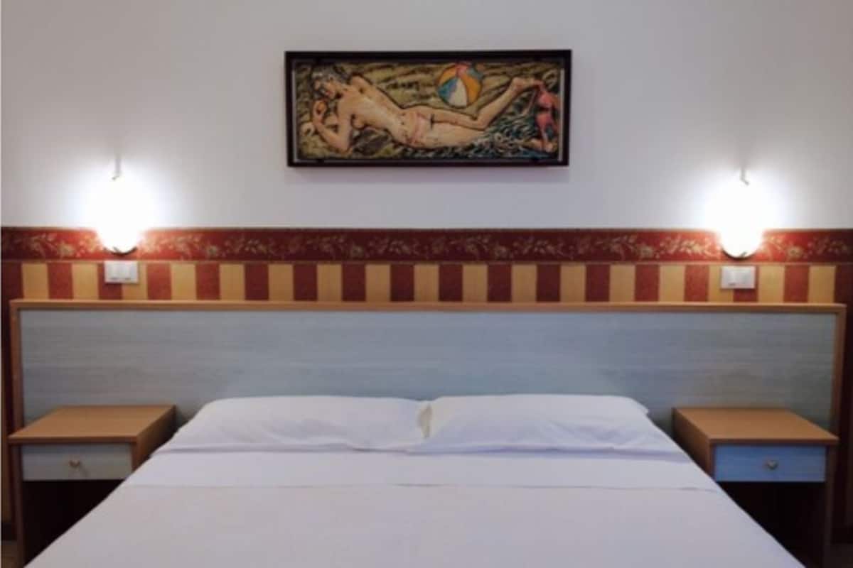 Ein Hotelzimmer mit einem Bett, zwei Nachttischen und einem Bild an der Wand.