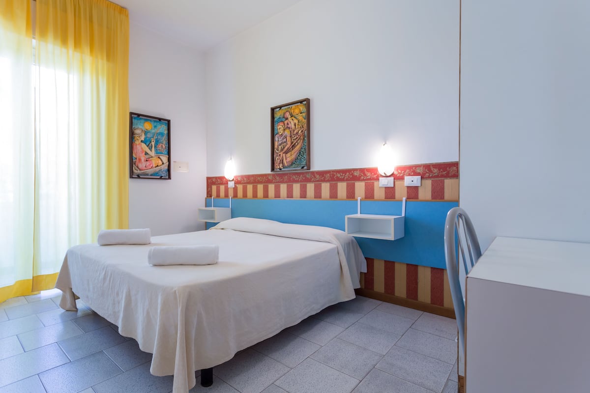 Ein Hotelzimmer mit einem Bett, einem Schreibtisch und zwei Wandleuchten.