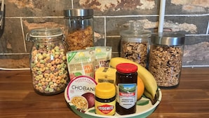 A variety of food items including cereal, yogurt, and honey on a kitchen counter. - Kookaburra Cottage (Burra)