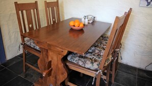 A wooden dining table with a bowl of oranges and a salt shaker. - Griffiths Cottage (Burra)