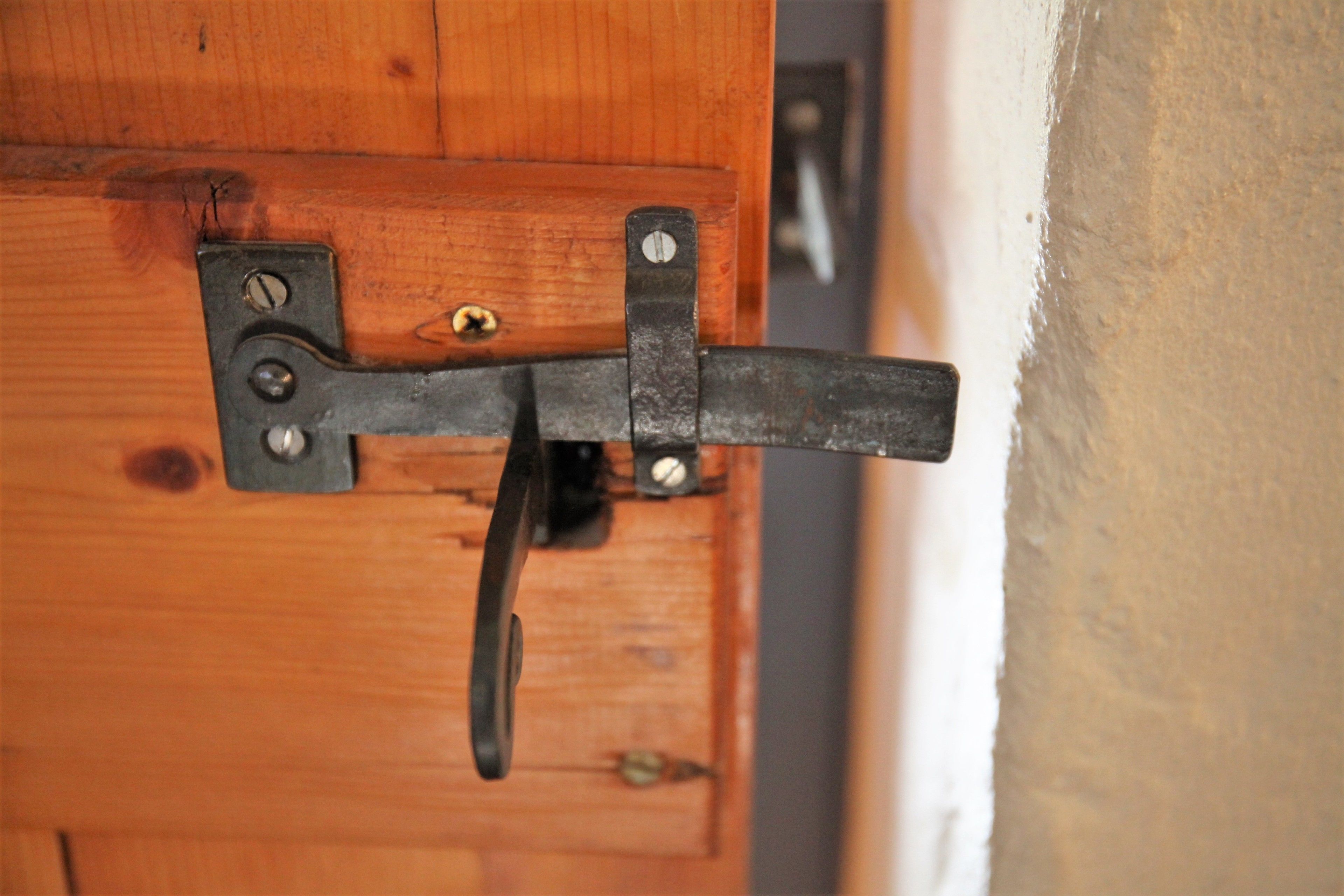 A wooden door with a metal latch and a handle.