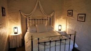 A four-poster bed with a canopy, two bedside tables with lamps, and framed pictures on the walls. - Griffiths Cottage (Burra)
