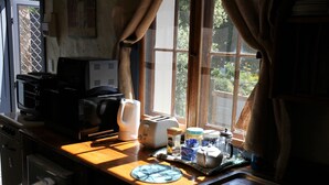 A kitchen with a wooden countertop, a toaster, a kettle, and a window with curtains. - Griffiths Cottage (Burra)