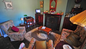 Een klassieke woonkamer met een open haard, meubels met een bloemenprint en een televisie.