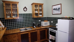 Una cocina con armarios de madera, microondas, horno y un lavamanos.