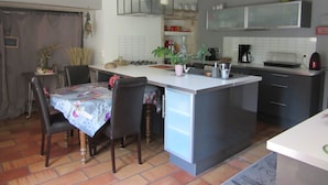 Une cuisine compacte dotée d’un îlot central, d’un coin repas avec des chaises et d’une petite table.