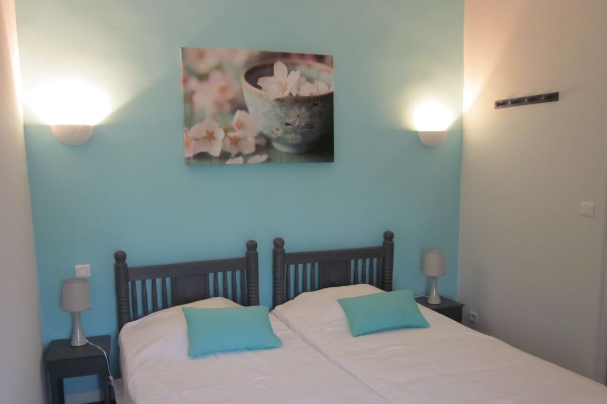 Ein Schlafzimmer mit zwei Betten, einem Wandbild, Nachttischlampen und einem Nachttisch.