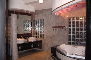 Une salle de bain spacieuse avec deux lavabos, une grande baignoire et une cabine de douche en verre.