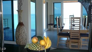 A dining area with a view of the sea, a vase with fruit, and wooden chairs. - 5 Bedroom Seaview Villa Tongson Bay (Koh Samui)