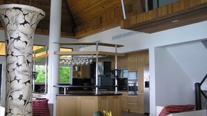A modern kitchen with wooden cabinets, a central island, and a large decorative vase. - 5 Bedroom Seaview Villa Tongson Bay (Koh Samui)