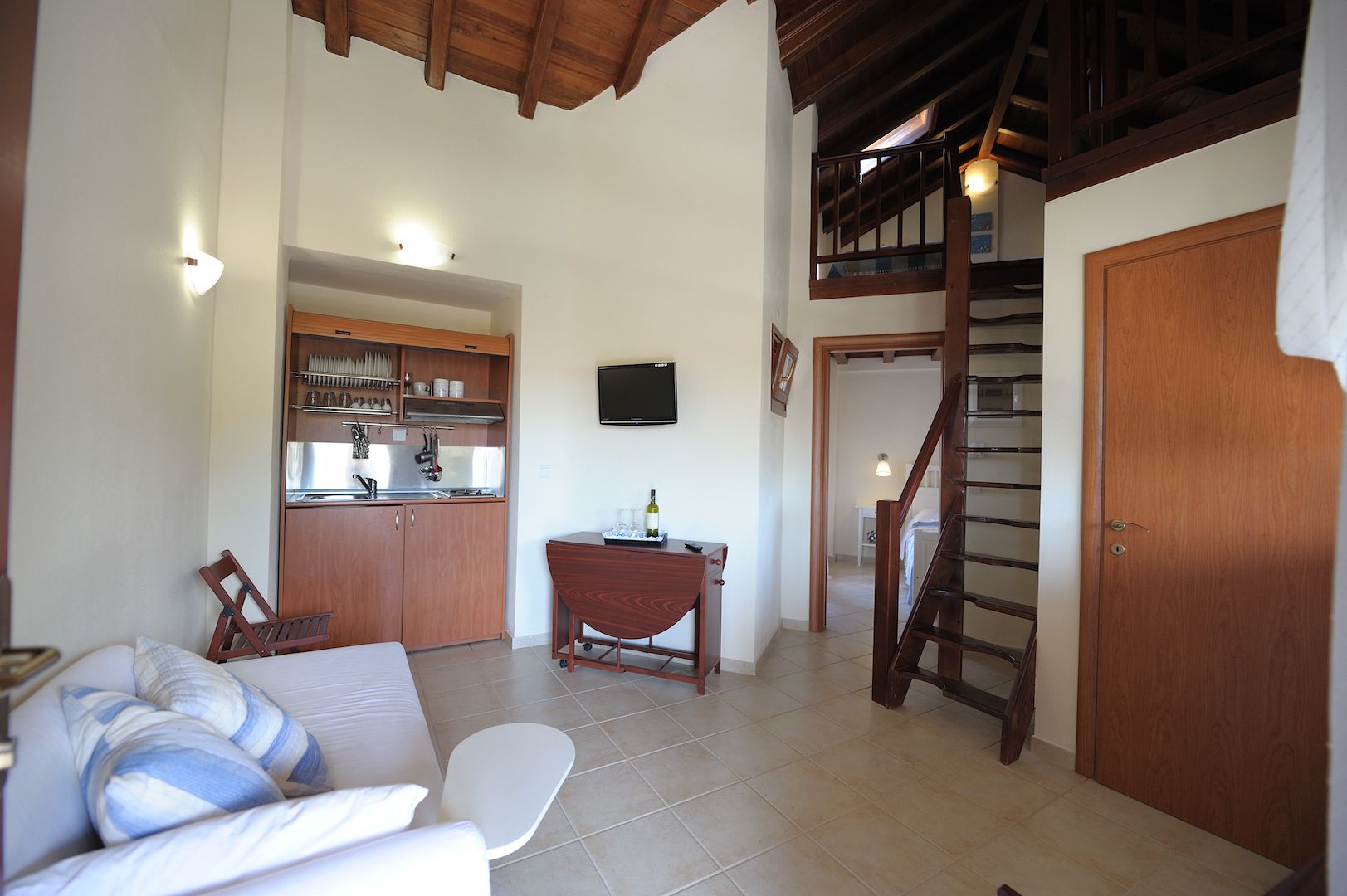 A spacious living area with a kitchen, a dining table, a sofa, and a staircase.