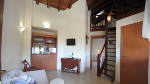 A spacious living area with a kitchen, a dining table, a sofa, and a staircase. - Xenonas Liogerma (Aristotelis)