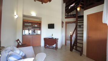 A spacious living area with a kitchen, a dining table, a sofa, and a staircase.