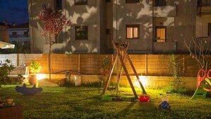 A well-maintained backyard with a swing set, a small tree, and a play area. - Xenonas Liogerma (Aristotelis)