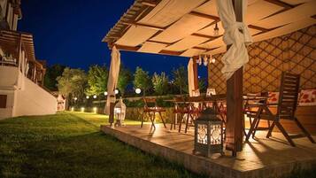 An outdoor patio area with tables and chairs, a lantern, and a pergola structure.