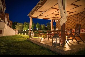 An outdoor patio area with tables and chairs, a lantern, and a pergola structure. - Xenonas Liogerma (Aristotelis)