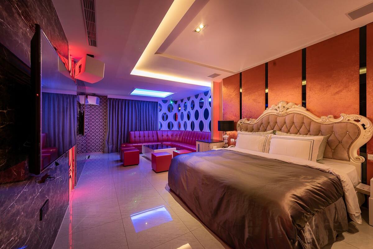 Una habitación de hotel moderna con una cama grande, un área de descanso y un televisor.