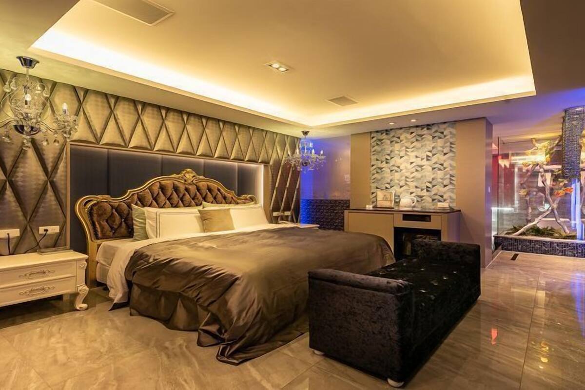 Un dormitorio moderno con una cama grande, una mesita de noche, un aparador y un área de descanso.