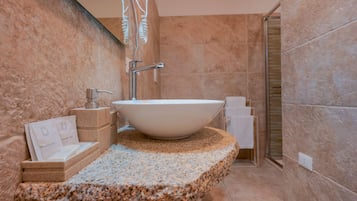 A bathroom with a granite countertop, a white sink, and a shower area.