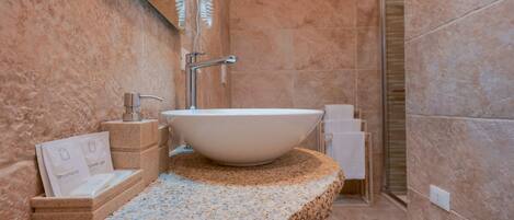 A bathroom with a granite countertop, a white sink, and a shower area.
