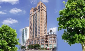 A high-rise building with a classic architectural style, surrounded by lush green trees.