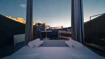 Une chambre d’hôtel avec un lit, un bureau et une vue sur le ciel nocturne.