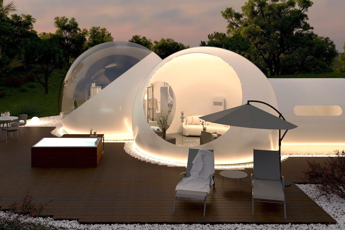 Eine moderne, kuppelartige Struktur mit spiegelnder Innenausstattung, umgeben von einer Holzterrasse und Sitzgelegenheiten im Freien.