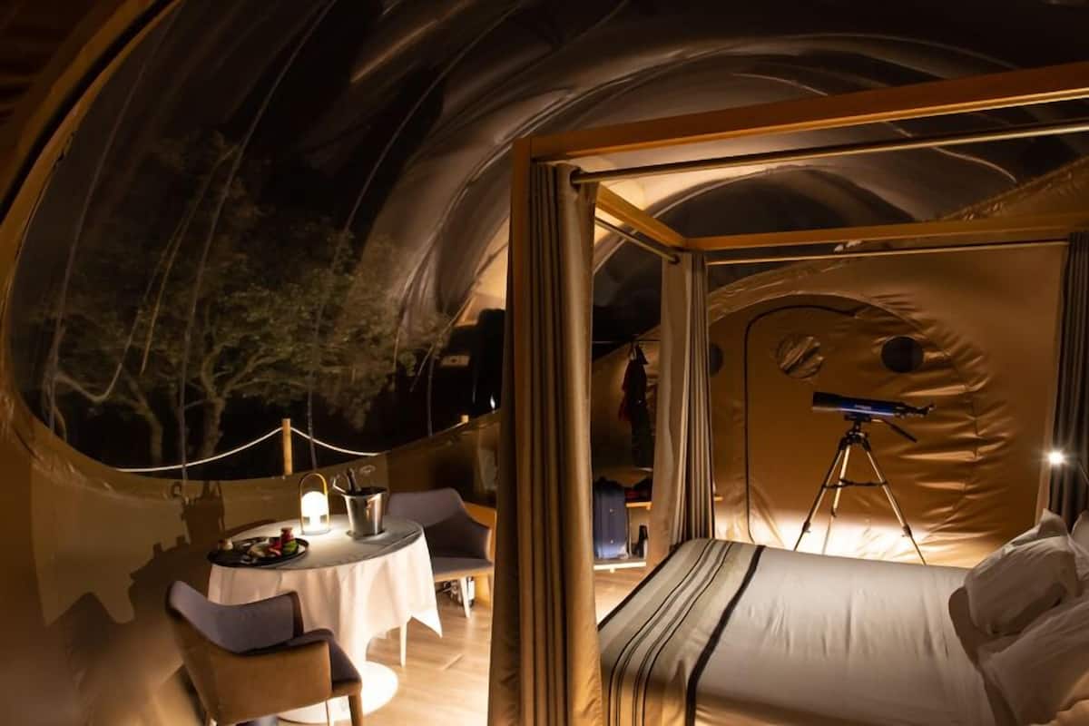 Eine Zelthütte mit einem Bett, einem Tisch mit Stühlen und einem Teleskop.