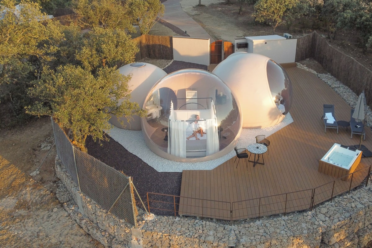 Ein Resort mit transparenten Kuppelkonstruktionen, einer Holzterrasse und Sitzgelegenheiten im Freien.