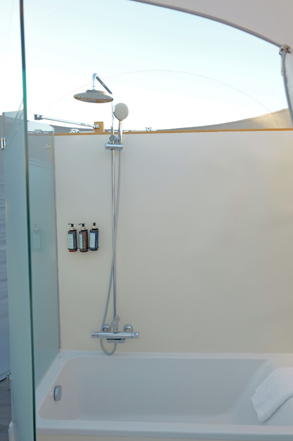 Un baño moderno con ducha de vidrio, bañera y dos botellas de champú en la pared.