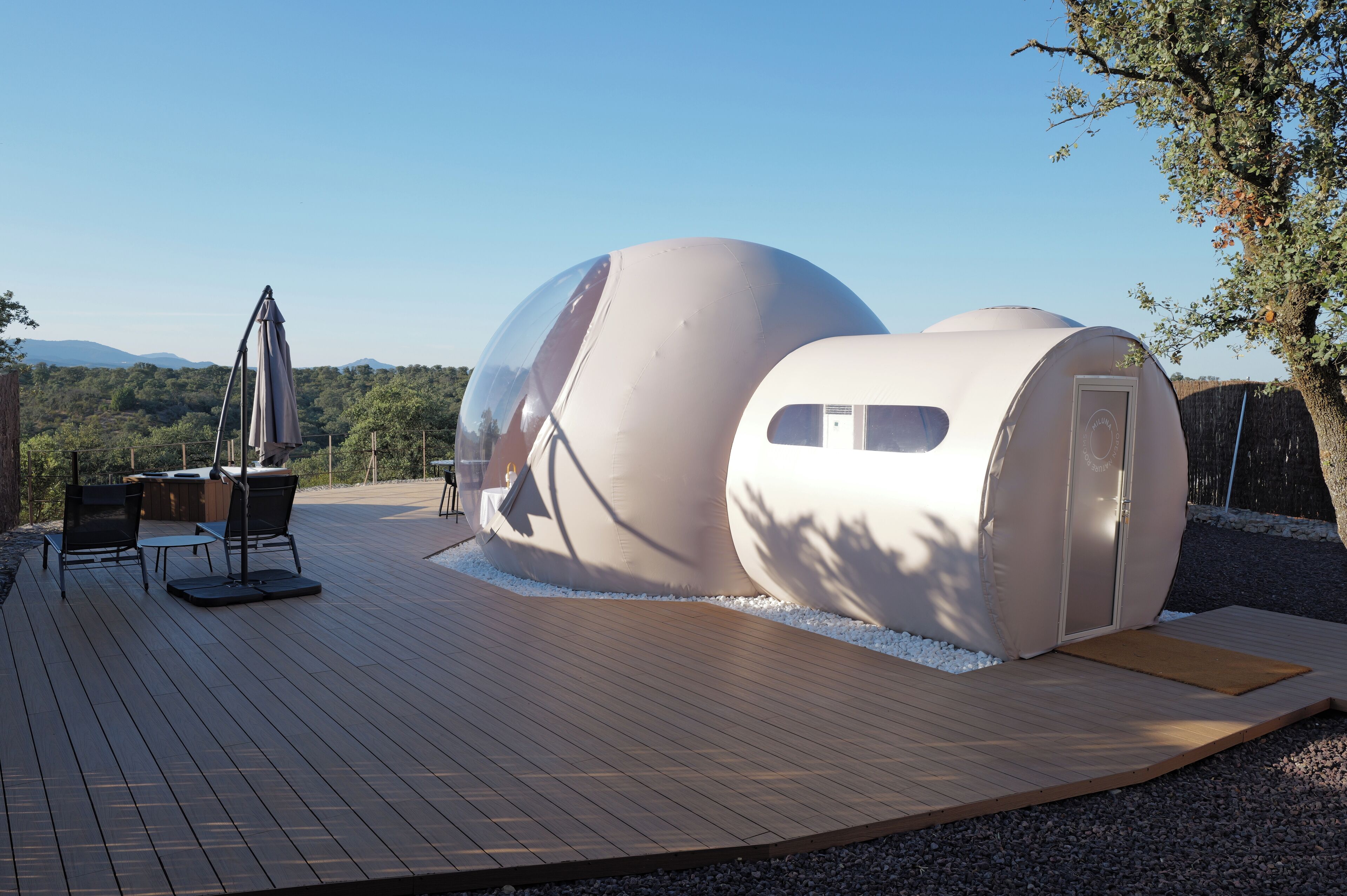 Dos estructuras esféricas con terraza de madera y zona de estar al aire libre.