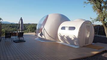 Dos estructuras esféricas con terraza de madera y zona de estar al aire libre.