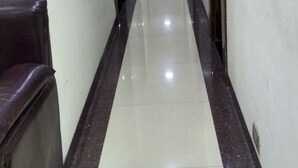A long, narrow hallway with a shiny floor, doors on both sides, and a red sign on the wall. - Hotel Plaza Mumbai (Mumbai)