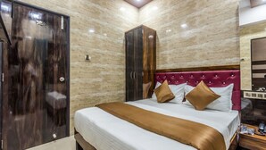 A bedroom with a bed, a wardrobe, and a nightstand. - Hotel Plaza Mumbai (Mumbai)