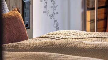 A cozy bed with a textured blanket, a wooden headboard, and a wall-mounted light fixture.