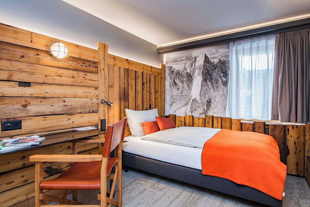 A wooden-paneled room with a bed, a desk, and a chair.