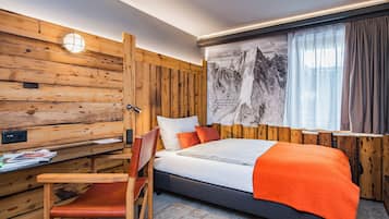 A wooden-paneled room with a bed, a desk, and a chair.