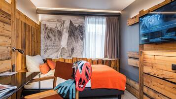 A room with a bed, wooden walls, a large window, a TV, and a mountain artwork.