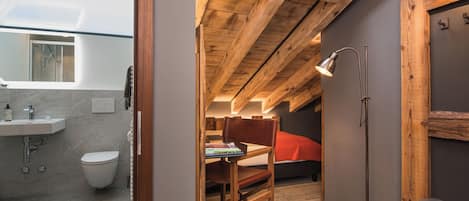 Un baño moderno y compacto con tragaluz, una silla de madera y una mesita de noche.