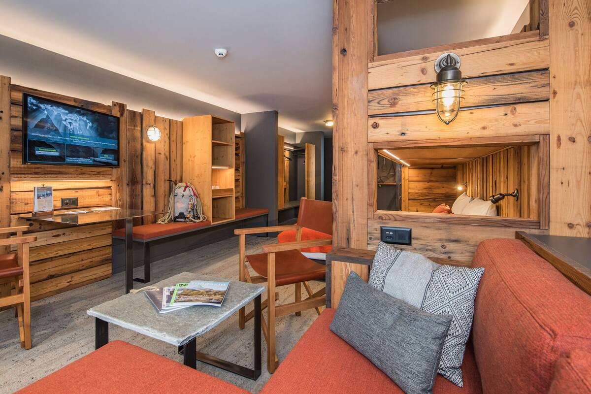 A cozy, rustic interior with wooden walls, a large flat-screen TV, seating areas, and a fireplace.