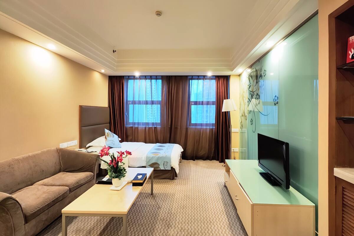 Een hotelkamer met een bed, een slaapbank, een televisie en een bureau.