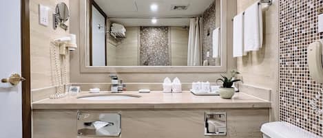 Een moderne badkamer met een grote spiegel, een wastafel, een handdoekrek, een prullenbak en een toilet.